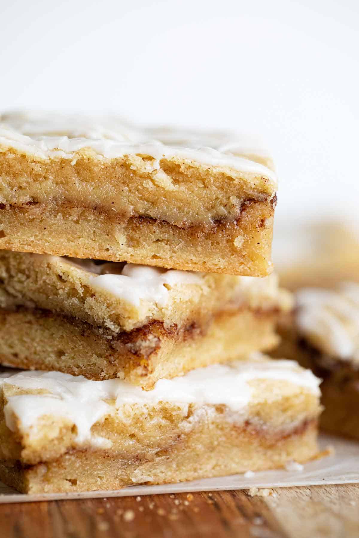 These Snickerdoodle Bars have two homemade layers with a cinnamon sugar layer in between. They taste like your favorite snickerdoodle cookies in bar form! Finish them off with a simple glaze for that extra touch. stack of snickerdoodle bars