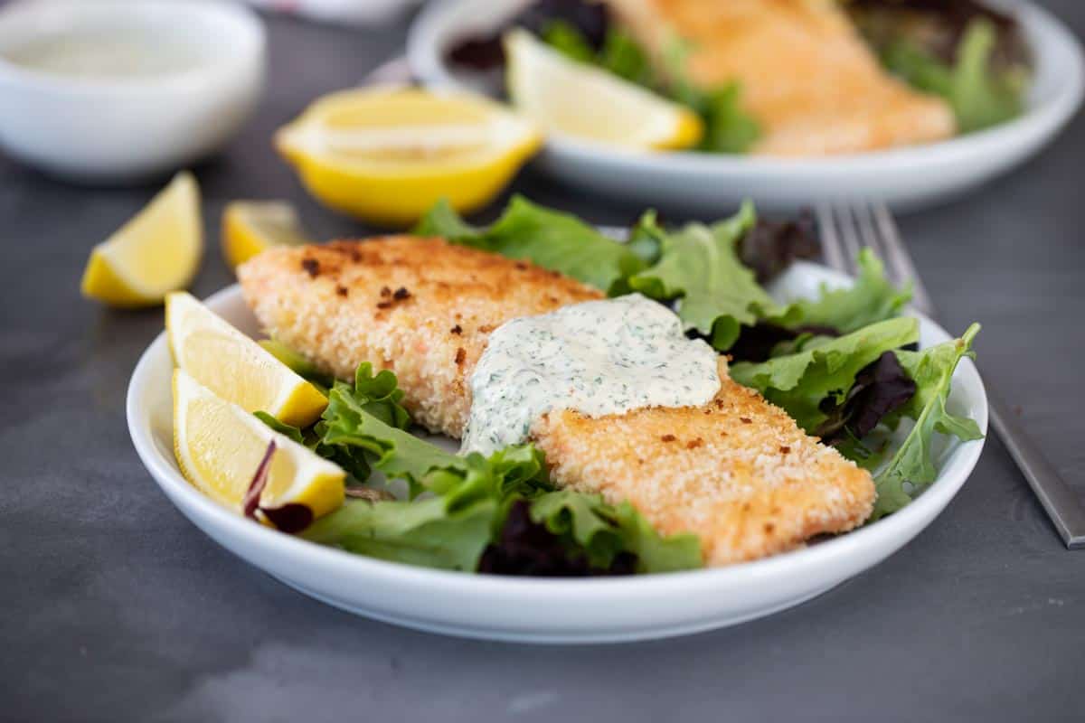 An easy weeknight dinner, this Pan Fried Salmon with Remoulade looks fancy but is super simple! Panko crusted salmon is cooked on the stovetop with a simple, flavorful sauce. pan fried salmon on a plate with sauce