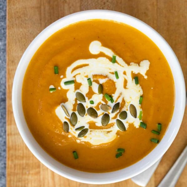 overhead view of a bowl of pumpkin soup on a cutting board