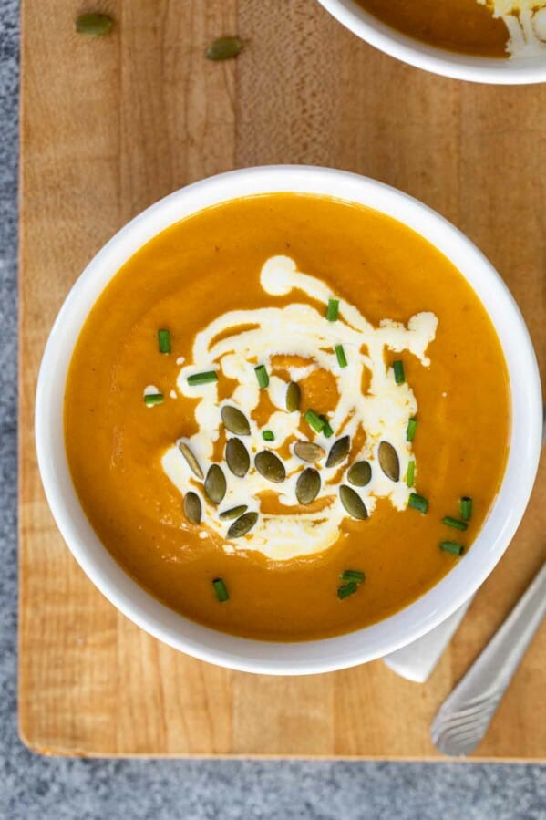 overhead view of a bowl of pumpkin soup on a cutting board