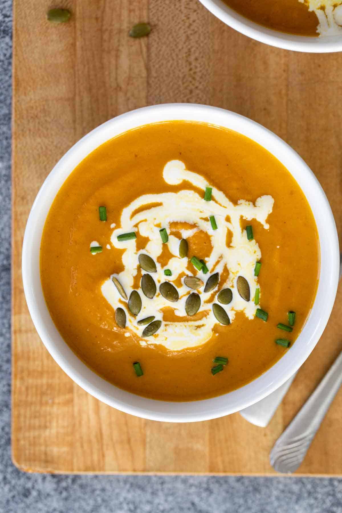 overhead view of a bowl of pumpkin soup on a cutting board