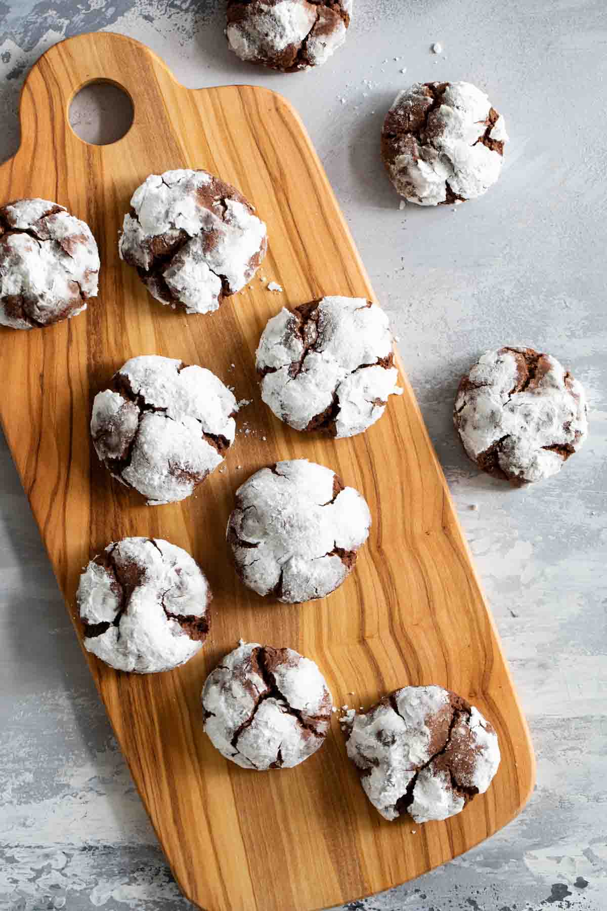 chocolate crinkle cookies dusted in powdered sugar on a wooden board.