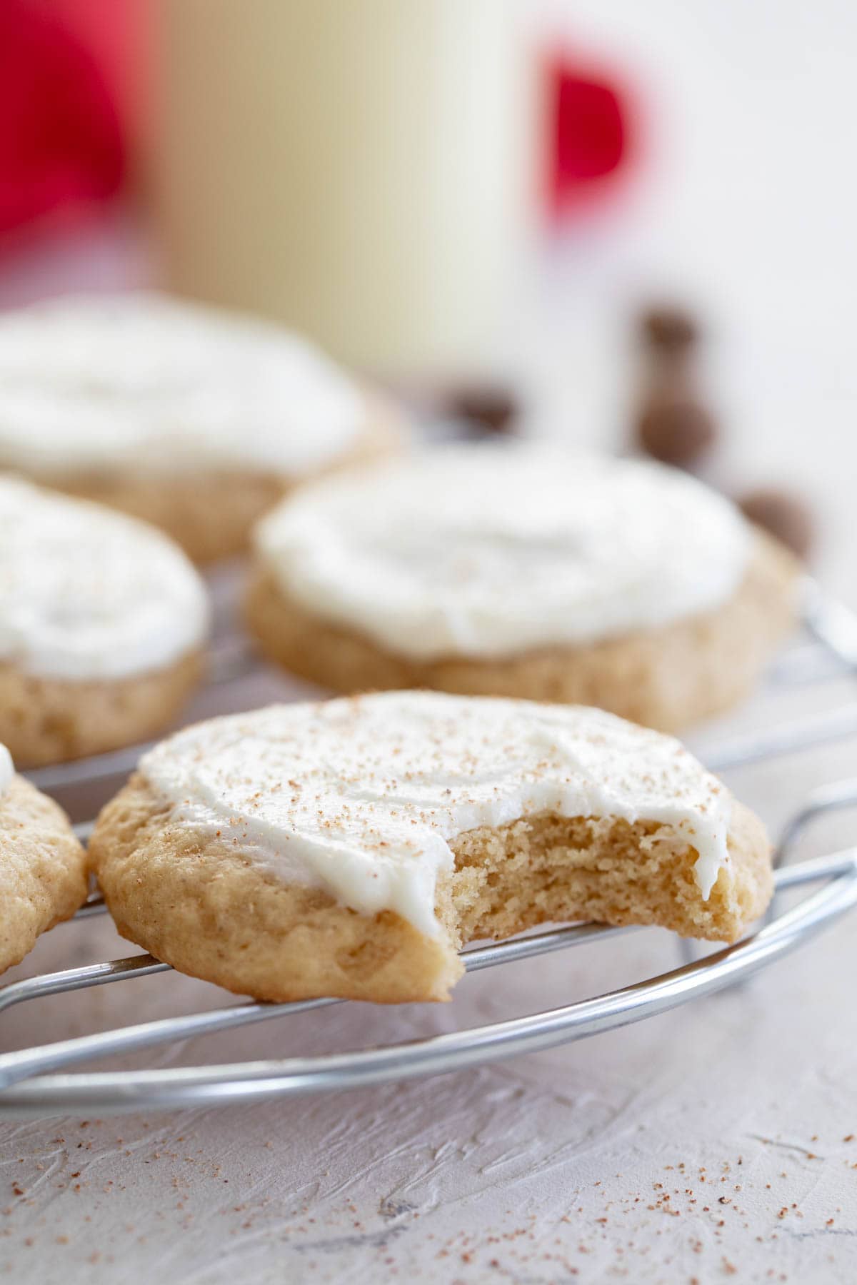 Eggnog cookies on a cooling rack with a bite taken from one cookie.
