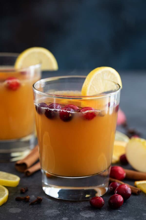 Hot Apple Cider in glasses with cranberries floating on top.