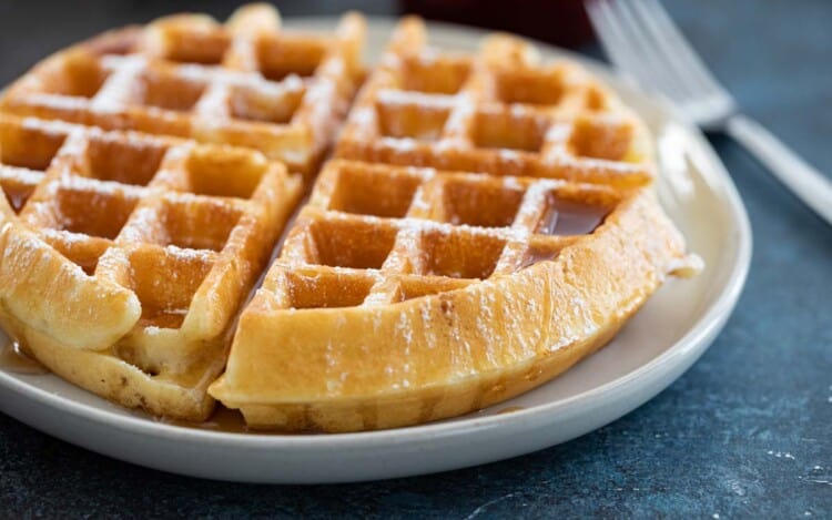 waffle on a plate with syrup and powdered sugar