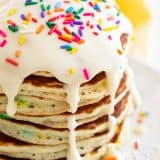 large stack of funfetti pancakes topped with icing and sprinkles