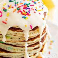 large stack of funfetti pancakes topped with icing and sprinkles