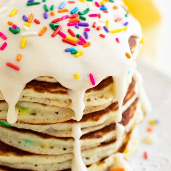 large stack of funfetti pancakes topped with icing and sprinkles