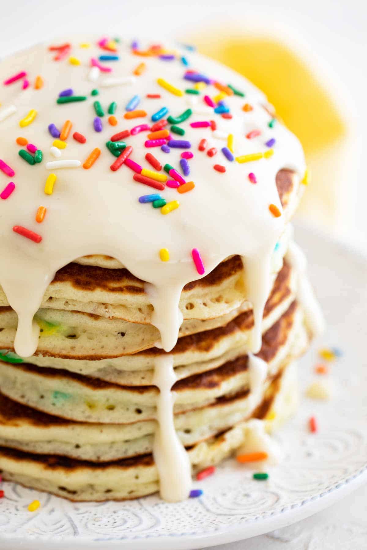 large stack of funfetti pancakes topped with icing and sprinkles