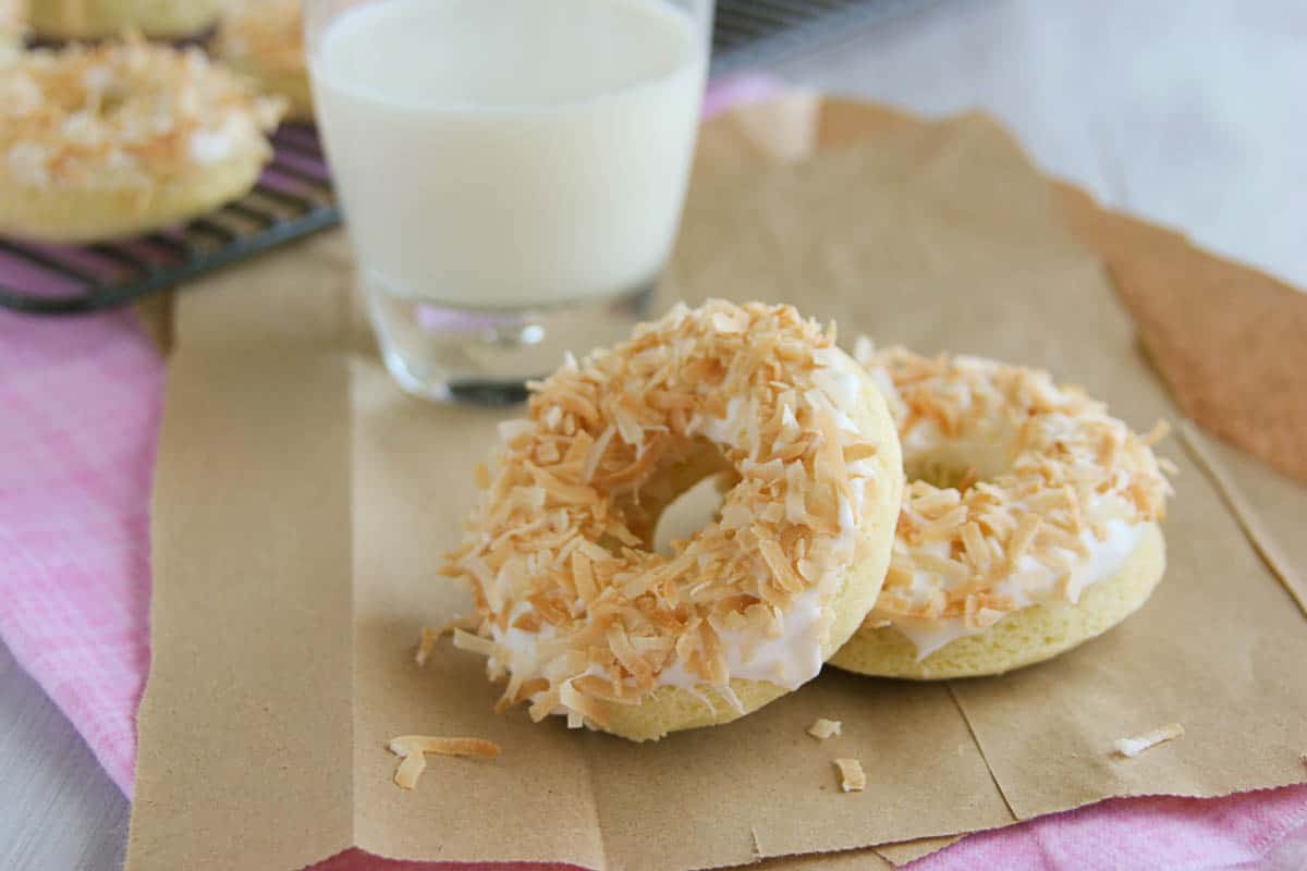 baked donuts topped with coconut icing and toasted coconut