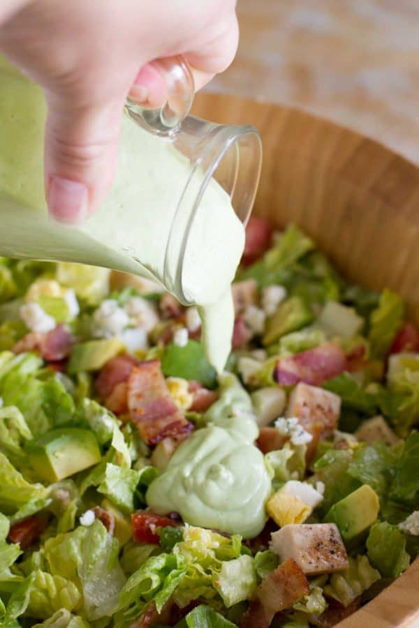 Pouring Avocado Ranch Salad Dressing on salad