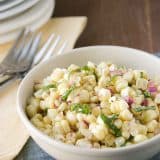 bowl of fresh corn salad topped with fresh basil.