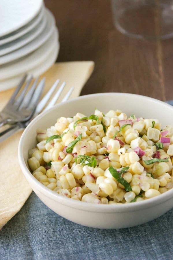 bowl of fresh corn salad topped with fresh basil.