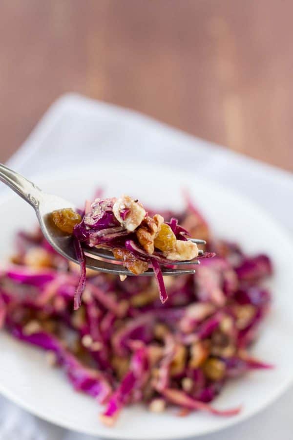bite of cabbage salad with golden raisins and walnuts