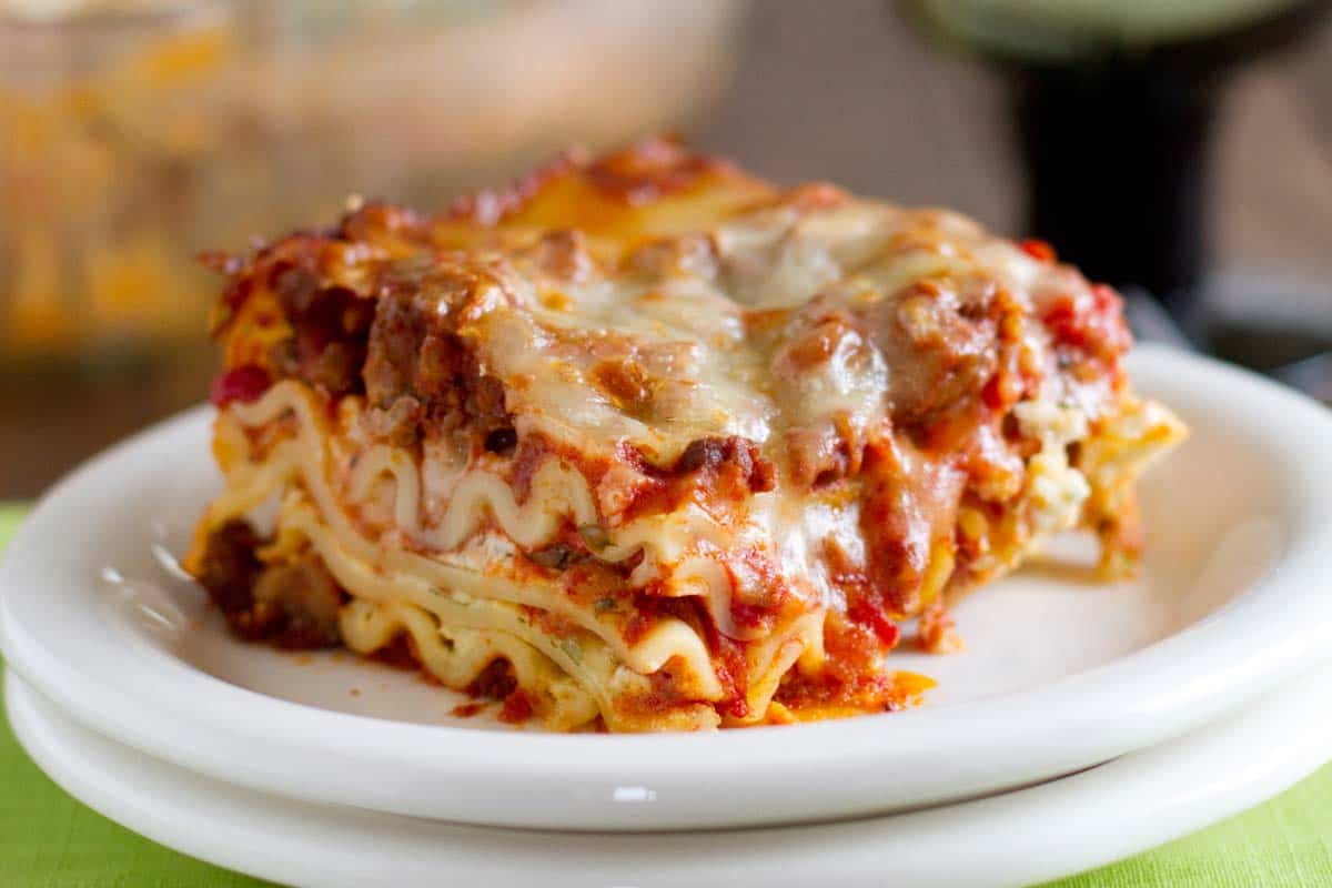 American Lasagna - A delicious lasagna recipe made with ground beef and sausage, with a little bit of brown sugar to give it something special. slice of American Lasagna on a white plate