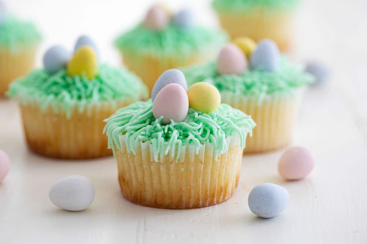 These Easter Cupcakes look and taste like spring! A light lemon cupcake is topped with a grass nest with Easter egg. These cupcakes are perfect for any Easter or Spring party. Lemon Cupcakes with Easter Decorations on top.
