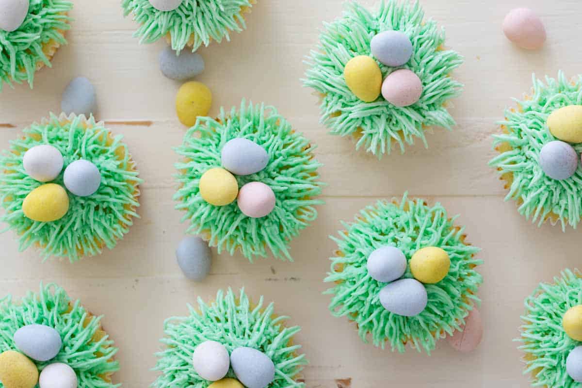 Easter cupcakes topped with green grass buttercream and Easter egg candy on top.