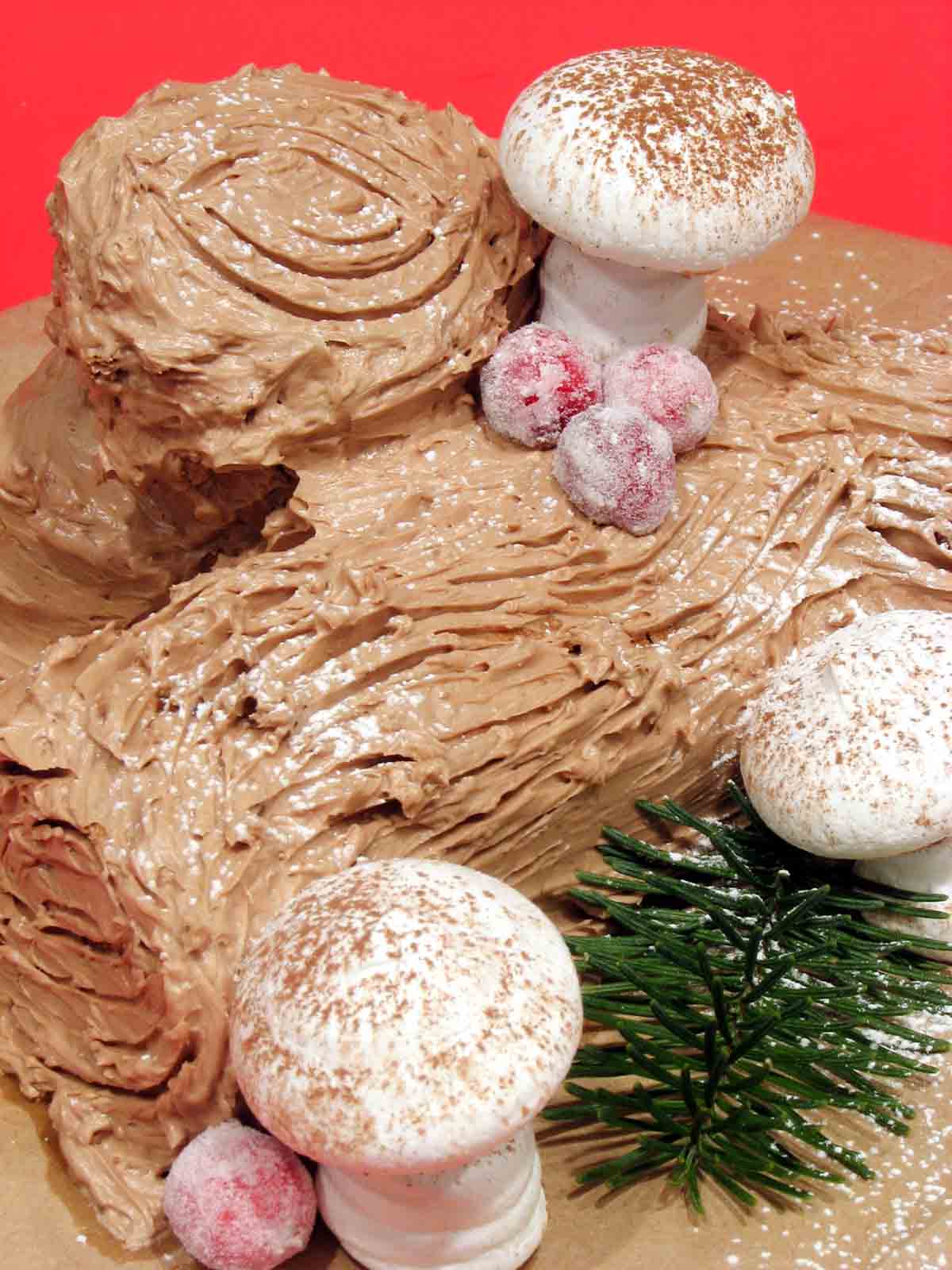 Chocolate Yule Log Cake topped with meringue mushrooms and sugared berries