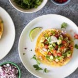 Tostada topped with beans, chicken and toppings