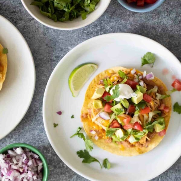 Tostada topped with beans, chicken and toppings