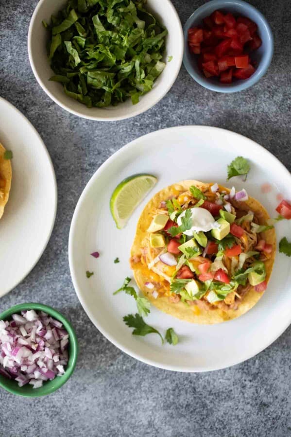 Tostada topped with beans, chicken and toppings