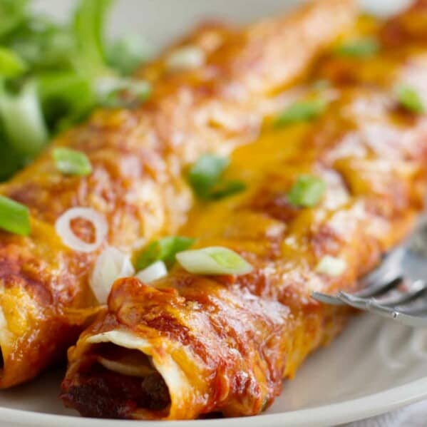 beef and bean enchiladas topped with red enchilada sauce