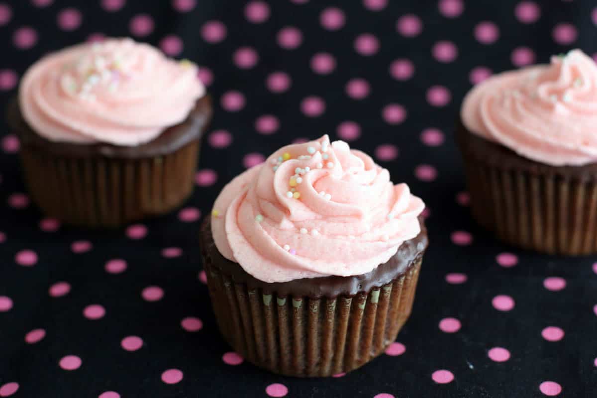 chocolate cupcakes topped with pink buttercream and sprinkles