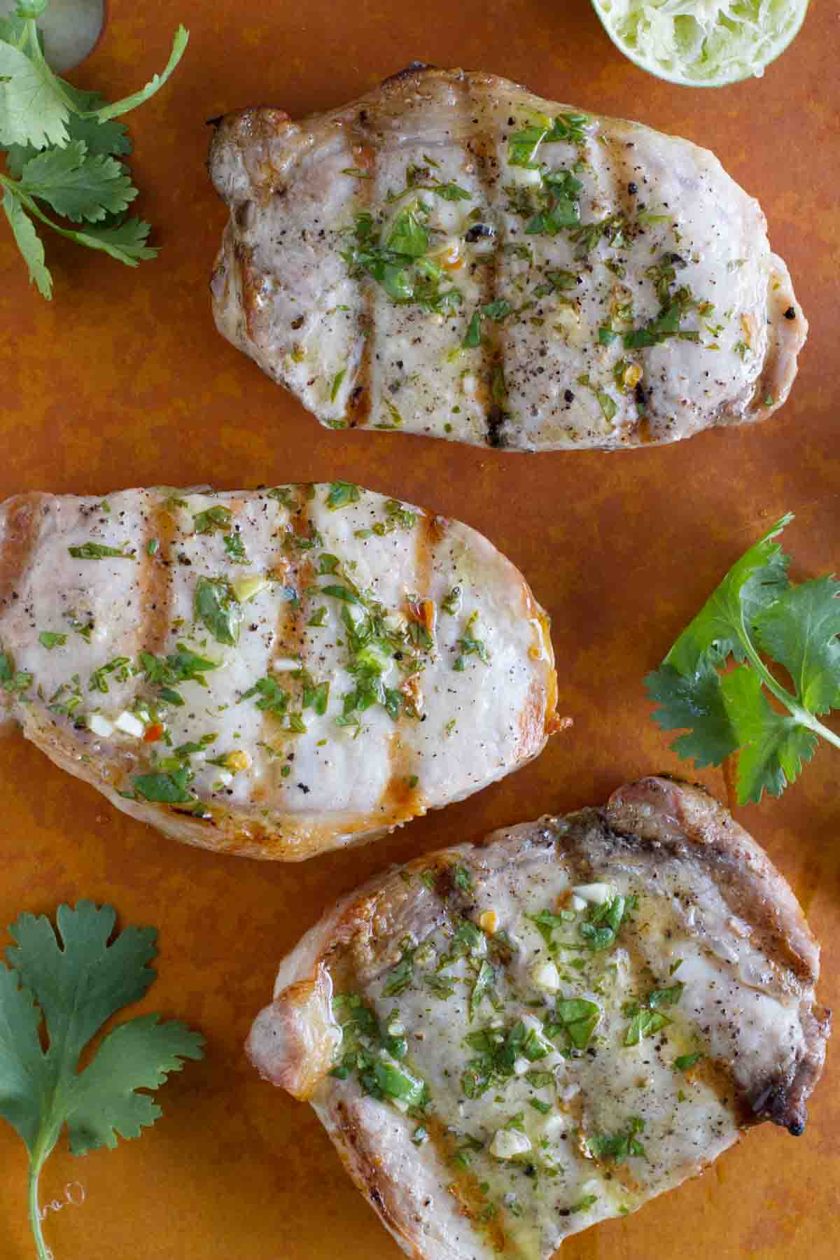 3 grilled pork chops topped with cilantro and lime