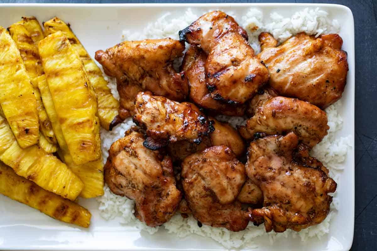 grilled chicken on a plate with rice and grilled pineapple