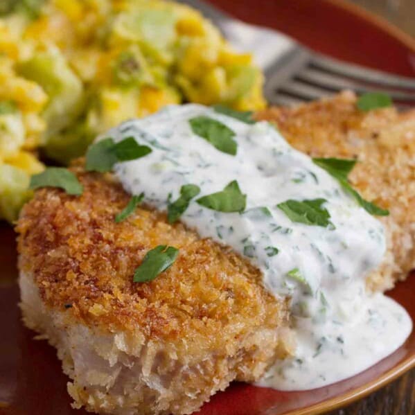 Plate with panko covered pork chop covered in a creamy herb dressing.