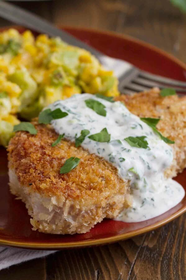 Plate with panko covered pork chop covered in a creamy herb dressing.