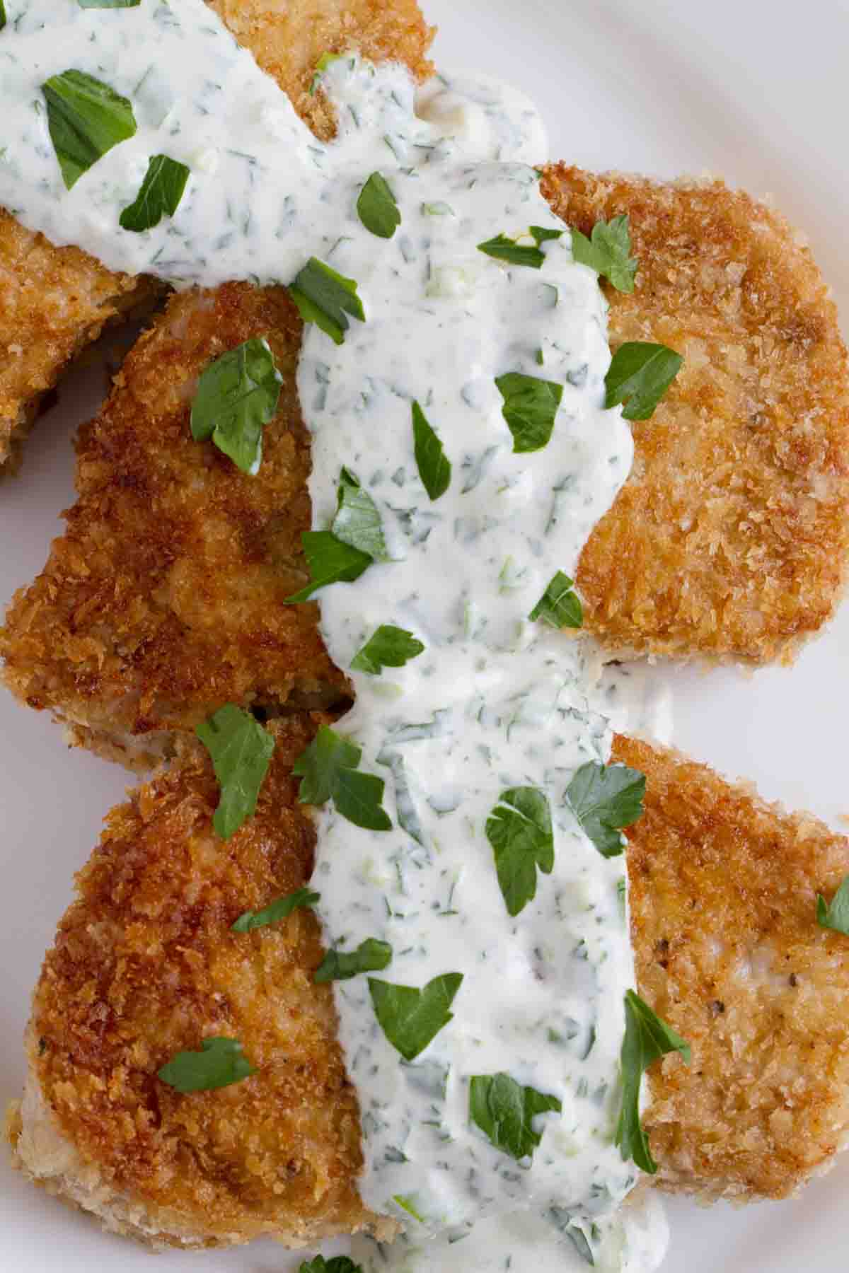 pork chops on a plate with creamy herb dressing.