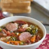 bowl of soup with sausage, beans and vegetables