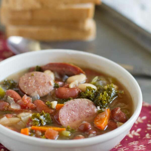 bowl of soup with sausage, beans and vegetables.