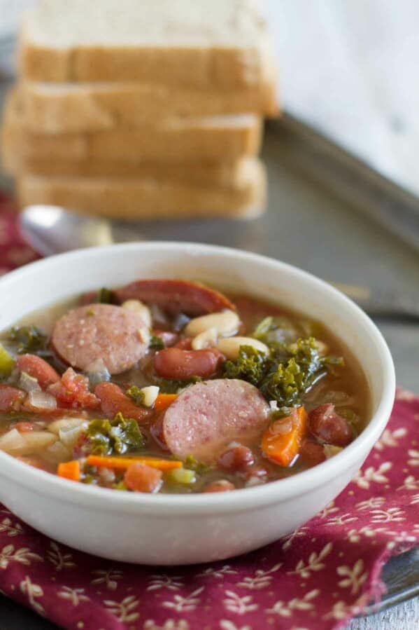 bowl of soup with sausage, beans and vegetables.