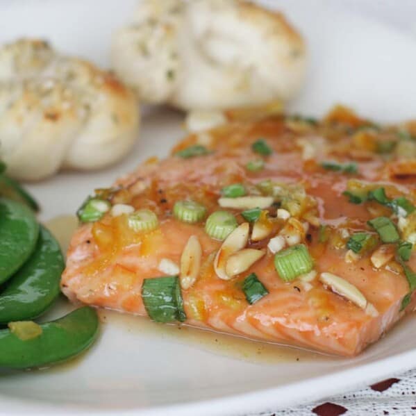 plate with citrus glazed salmon, sugar snap peas and parmesan rolls