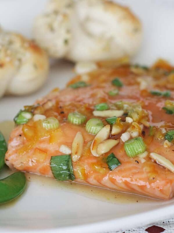 plate with citrus glazed salmon, sugar snap peas and parmesan rolls