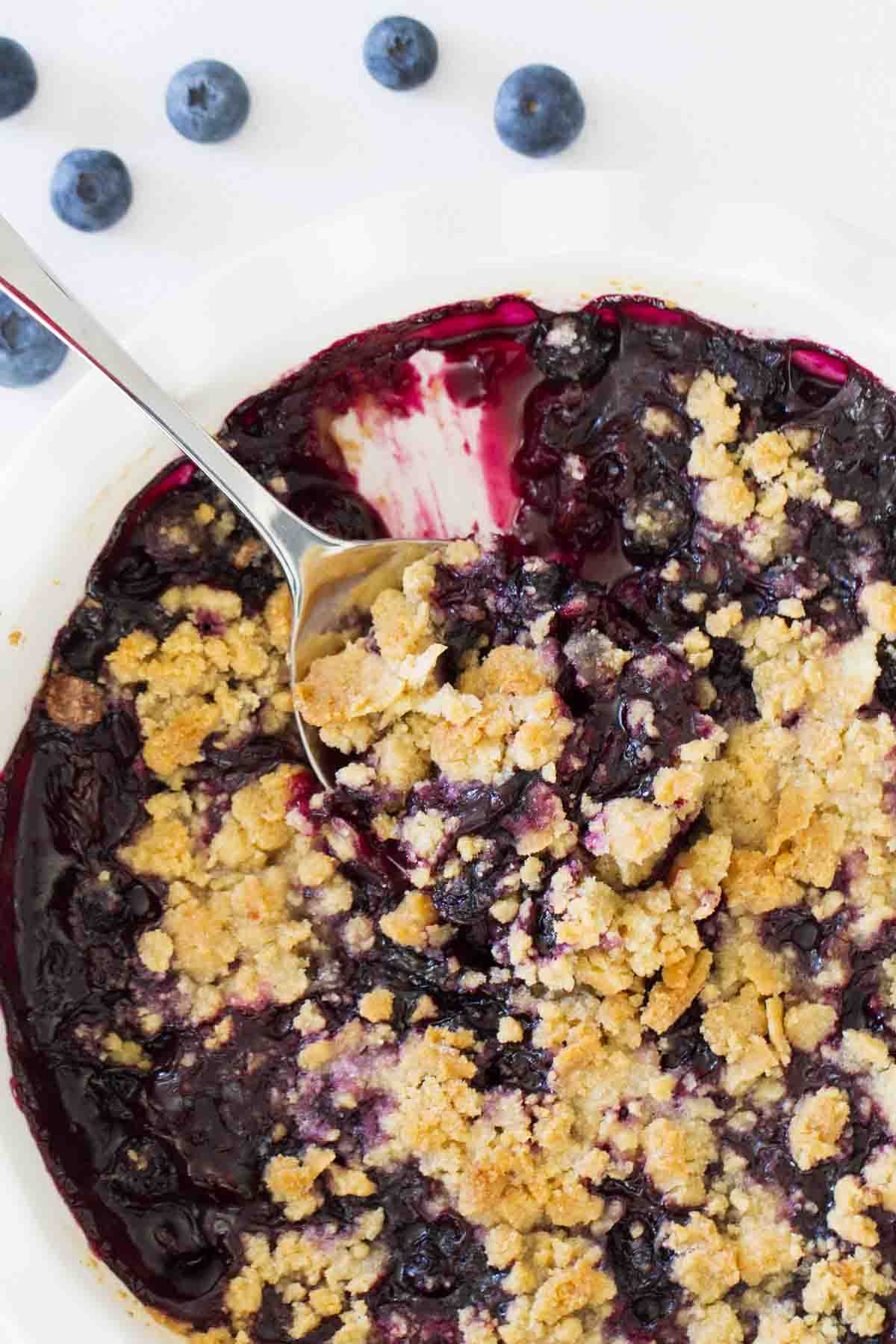 Dish of blueberry crisp with serving spoon