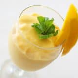 Mango Batido in a glass with mint and fresh mango