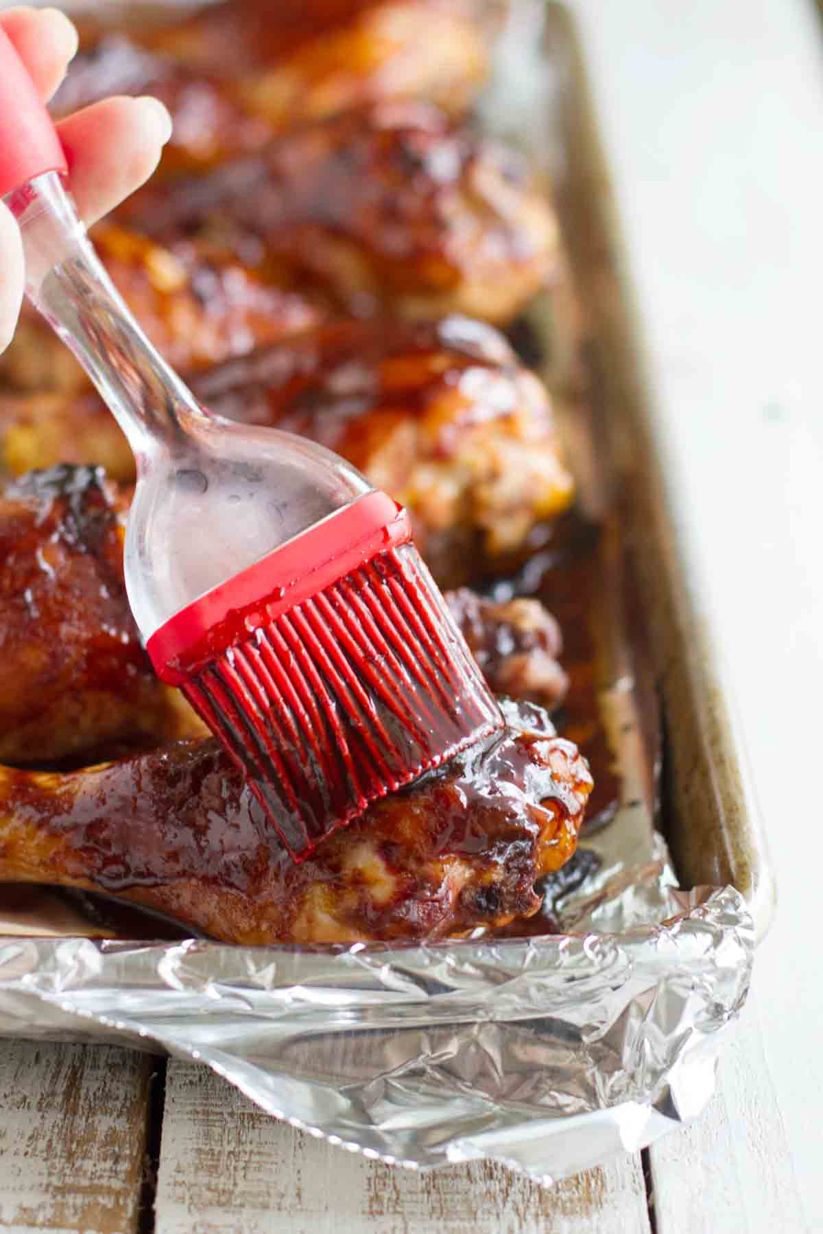 brushing sauce on chicken drumsticks