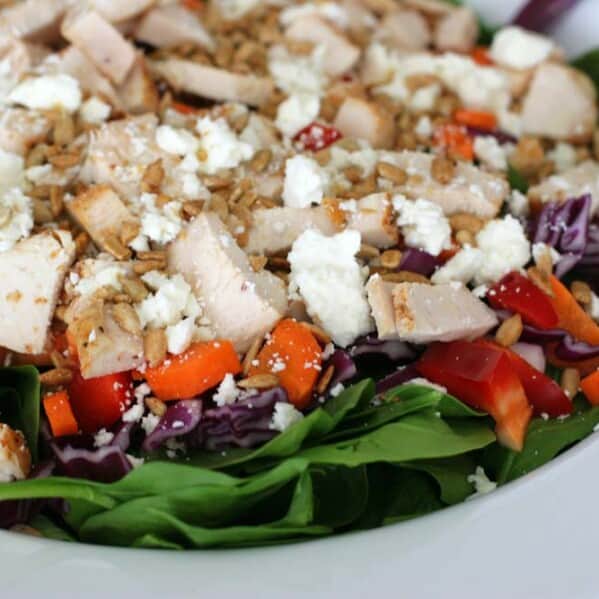 salad topped with chicken, vegetables and crumbled cheese
