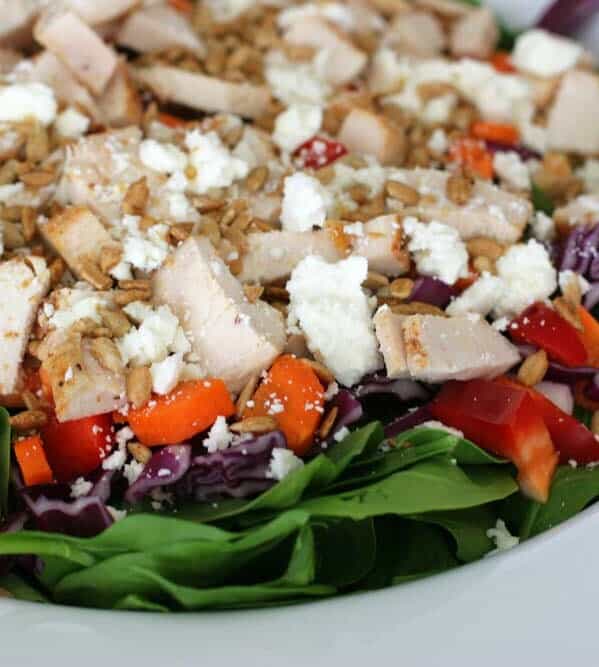 salad topped with chicken, vegetables and crumbled cheese