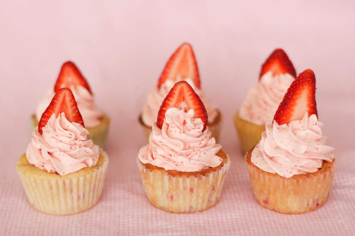 6 strawberry cupcakes with strawberry slices on top.