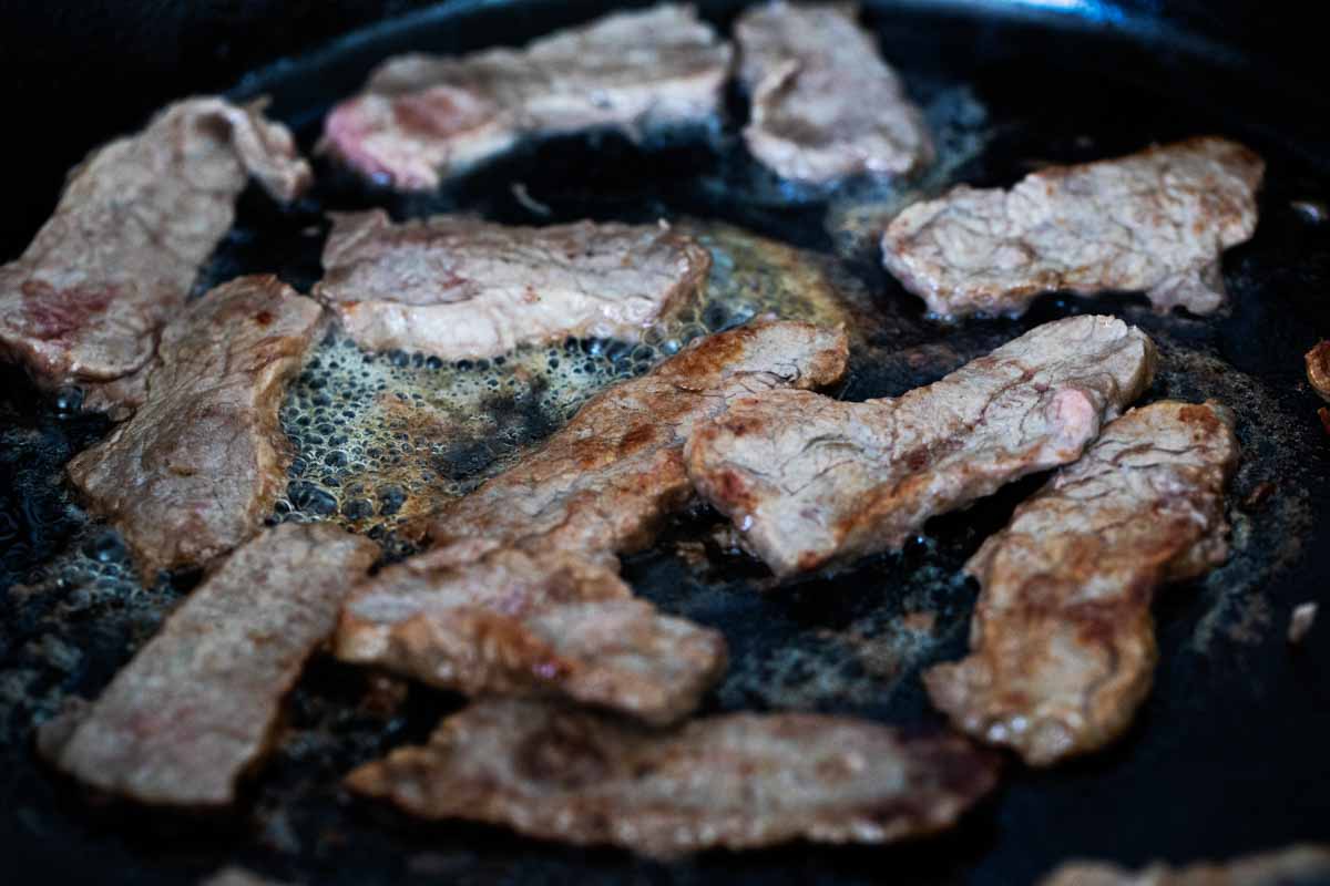 cooking strips of steak in cast iron