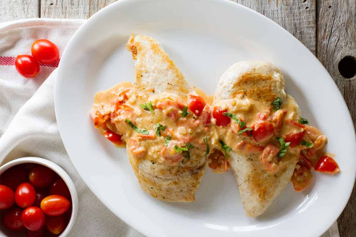 overhead view of chicken covered with a tomato and parmesan cream sauce