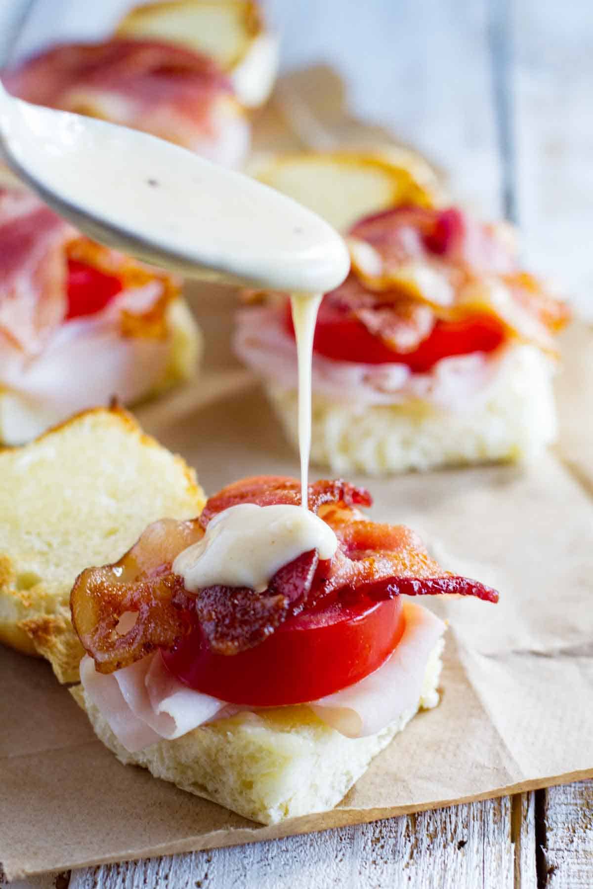 putting Mornay sauce over easy hot brown sandwiches