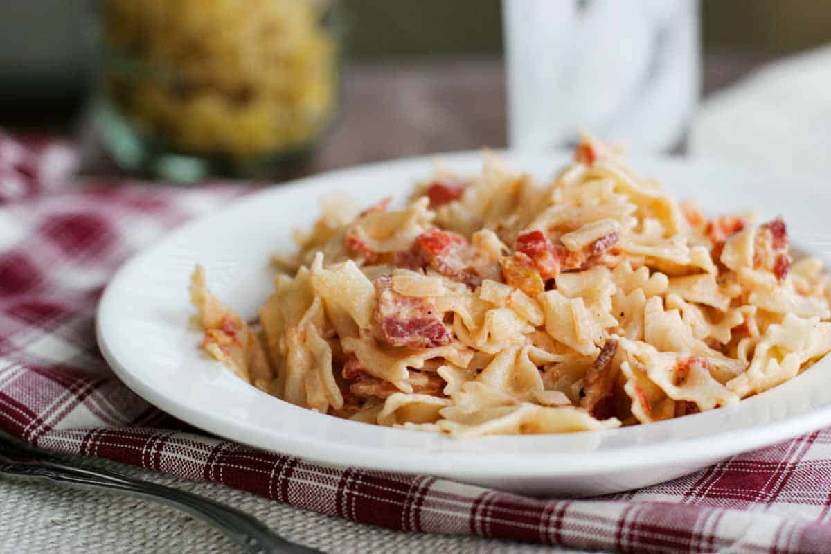 white plate with tomato bacon pasta