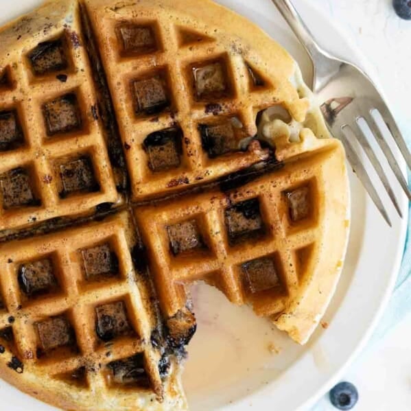 overhead view of blueberry waffle with syrup with a bite taken