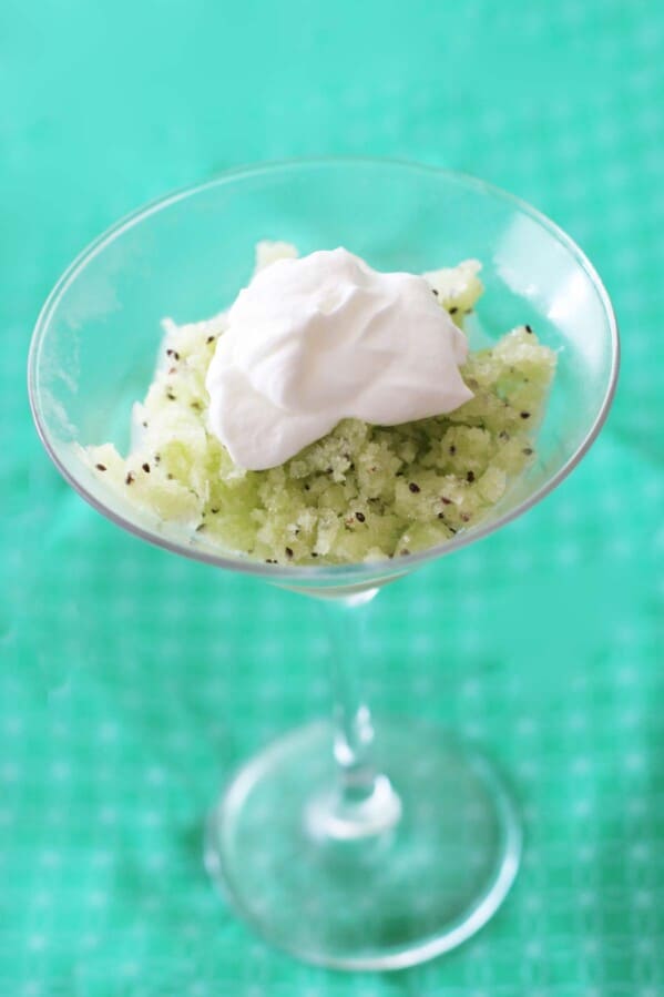 kiwi granita in a stemmed glass, topped with whipped cream
