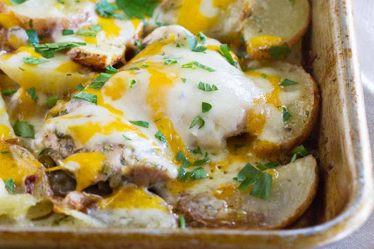 sheet pan with potatoes and chicken covered in melted cheese